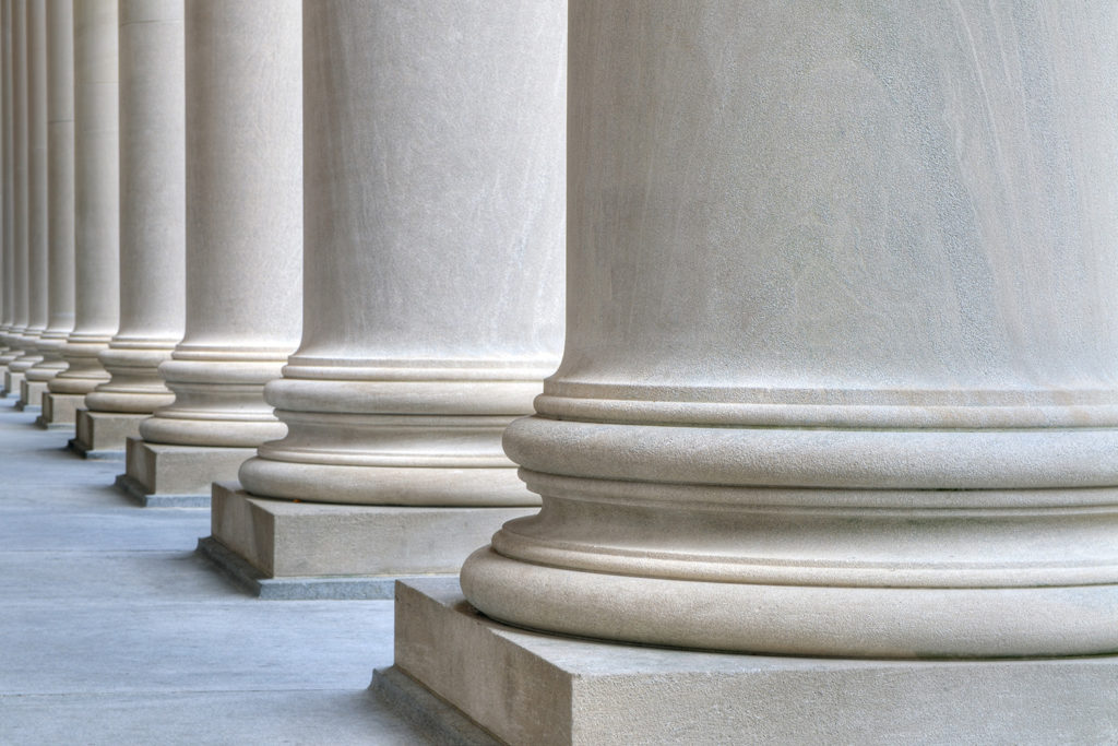 A closeup of the bottoms of a row of marble columns