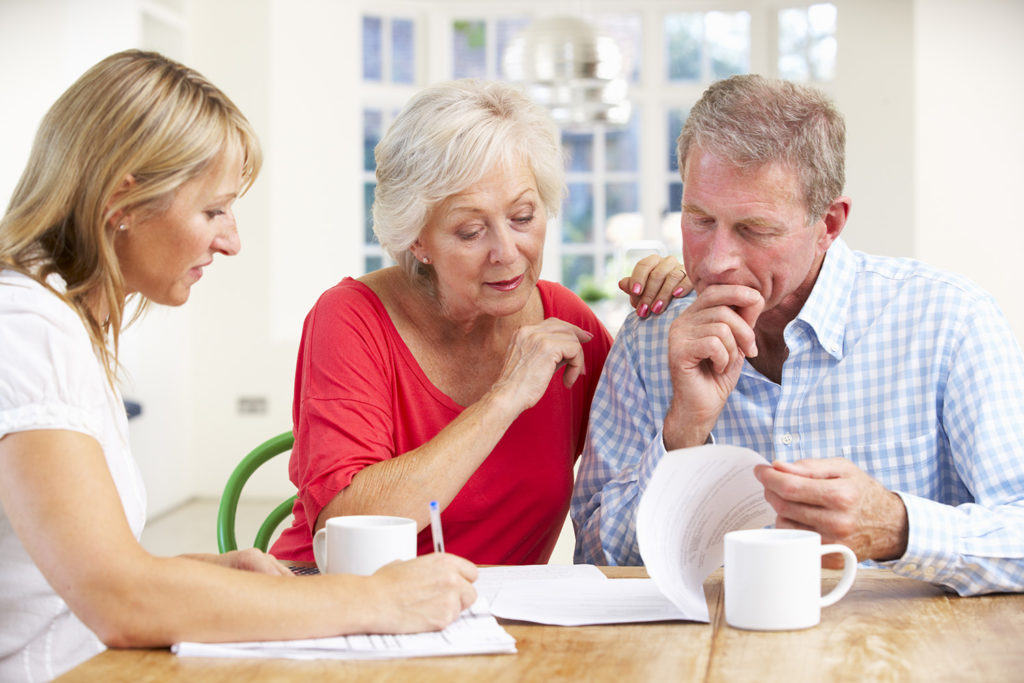A couple sits at their kitchen table with an advisor