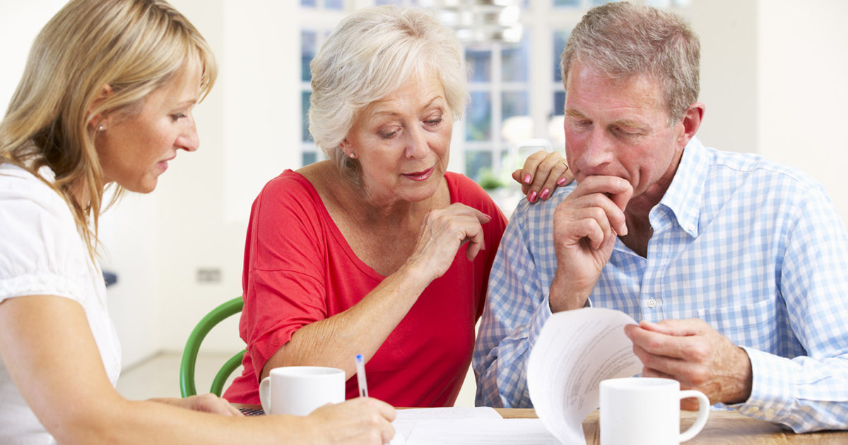 A couple sits at their kitchen table with an advisor